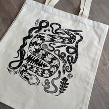 Load image into Gallery viewer, A sturdy canvas tote bag with a collection of illustrated snakes screen printed on it in black ink. The snakes include a timber rattlesnake, black rat snake, eastern hognose, ringneck, water snake, garter snake, and ribbon snake.