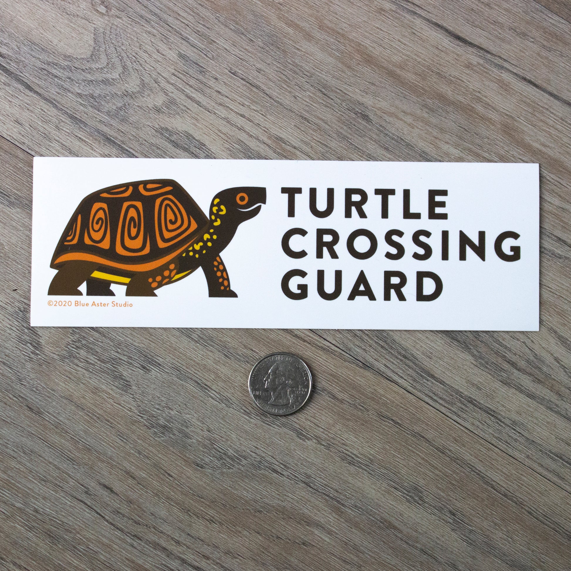 The turtle crossing guard bumper sticker next to a USD quarter for scale.