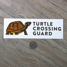 Load image into Gallery viewer, The turtle crossing guard bumper sticker next to a USD quarter for scale.