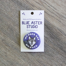 Load image into Gallery viewer, A 1.5 inch purple pinback button with an illustration of a wolf and the words My Pack Has My Back.