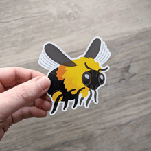 Load image into Gallery viewer, A hand holding a bumblebee vinyl sticker.