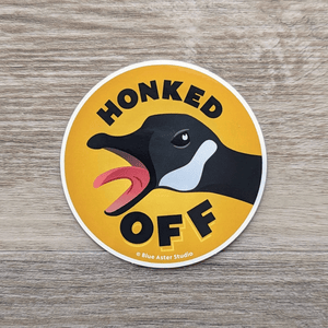 A round vinyl sticker that features an illustration of a Canada goose with its beak open and honking with the words "Honked Off" around it.