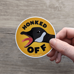 A hand holding the Honked Off Goose sticker.