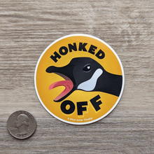 Load image into Gallery viewer, The honked off goose sticker next to a USD quarter to show scale.