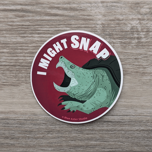 A round vinyl sticker featuring an illustration of a snapping turtle an the words 