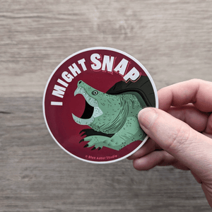 A hand holding the snapping turtle sticker.